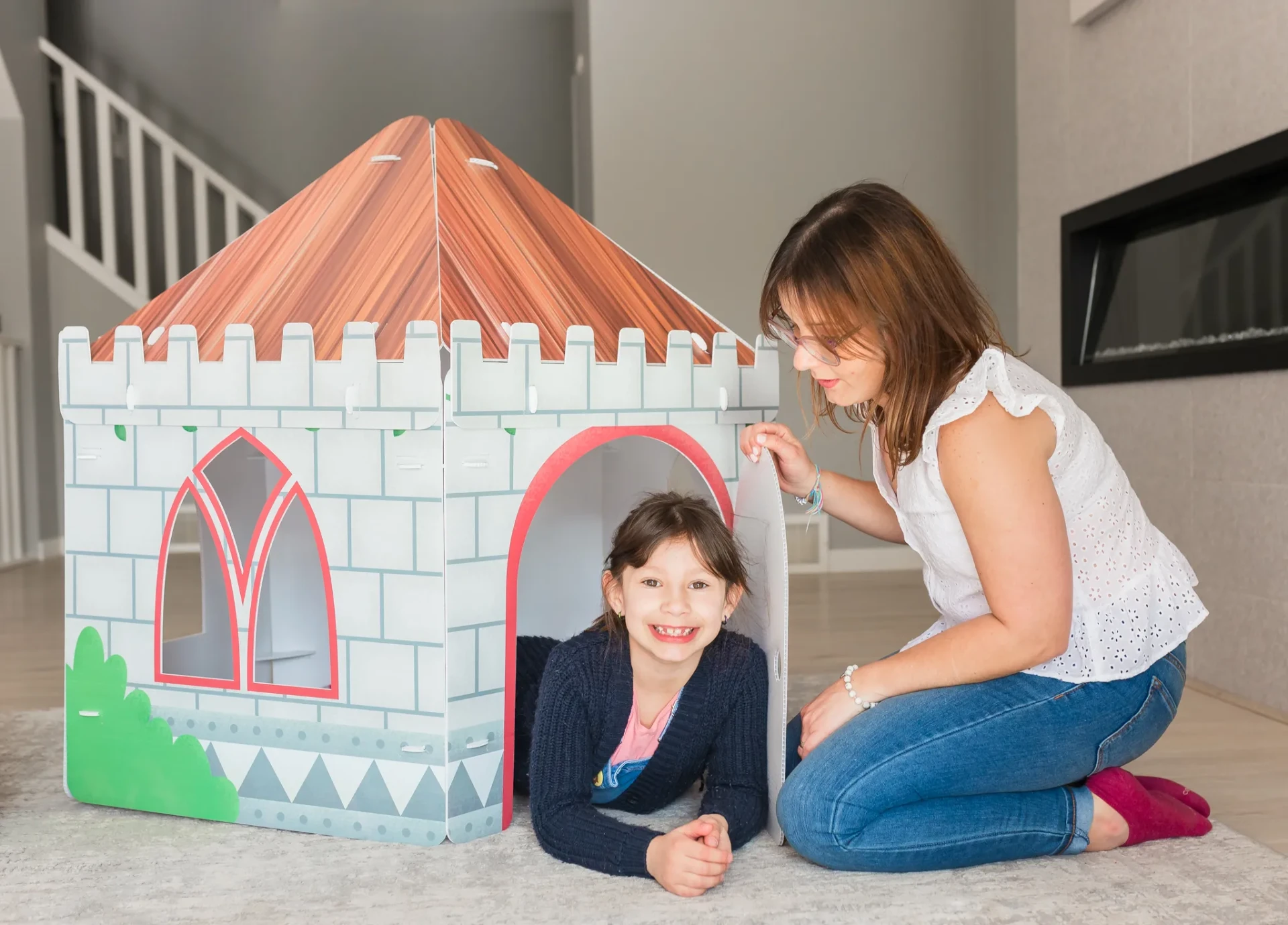 A mother beside her smiling daughter in a printed NimoPlay castle playhouse at home